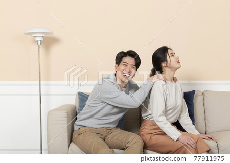 Asian wife massaging shoulders of husband Asian wife massaging shoulders of husband 77911975