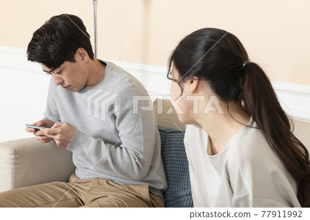Asian wife angry at at husband using smart phone on sofa Asian wife angry at at husband using smart phone on sofa 77911992