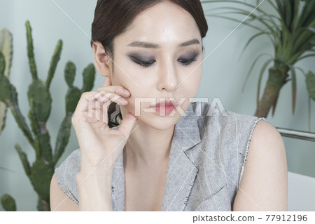 Asian female model in suit with dark smokey makeup, cactus background Asian female model in suit with dark smokey makeup, cactus background 77912196