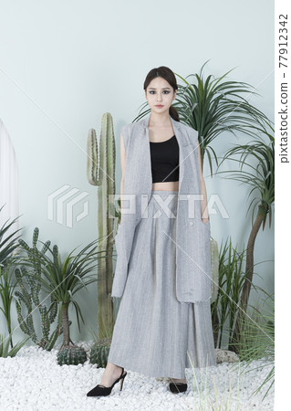 Asian female model in suit with dark smokey makeup, cactus background Asian female model in suit with dark smokey makeup, cactus background 77912342