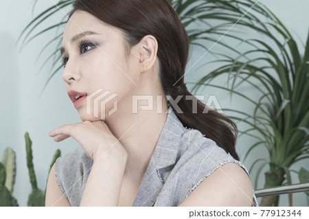 Asian female model in suit with dark smokey makeup, cactus background Asian female model in suit with dark smokey makeup, cactus background 77912344
