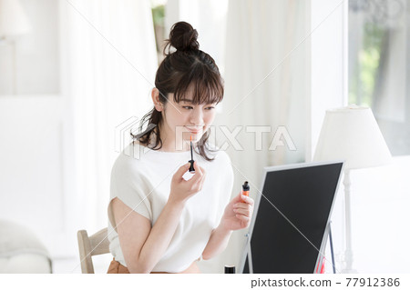 Woman doing make-up Woman doing make-up 77912386