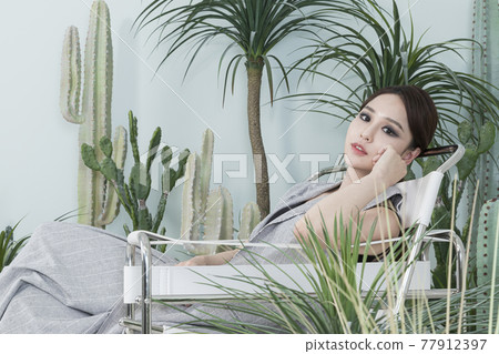 Asian female model in suit with dark smokey makeup, cactus background Asian female model in suit with dark smokey makeup, cactus background 77912397