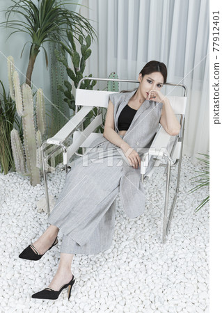 Asian female model in suit with dark smokey makeup, cactus background Asian female model in suit with dark smokey makeup, cactus background 77912401