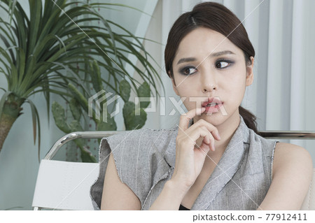 Asian female model in suit with dark smokey makeup, cactus background Asian female model in suit with dark smokey makeup, cactus background 77912411