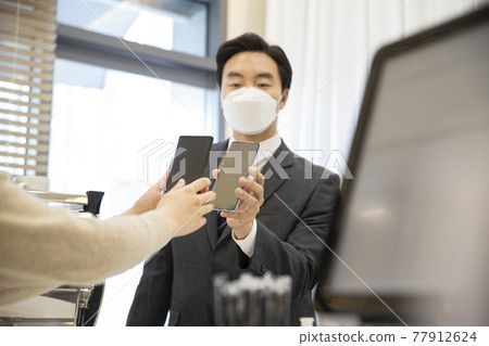 Asian businessman, customer entering store after sanitizing, measuring temperature, leaving QR log, business during covid virus concept Asian businessman, customer entering store after sanitizing, measuring temperature, leaving QR log, business during covid virus concept 77912624