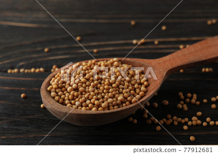 Wood spoon with mustard seeds on wooden background 77912681