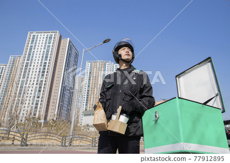 Asian delivery male courier on motorcycle, scooter delivering coffee Asian delivery male courier on motorcycle, scooter delivering coffee 77912895
