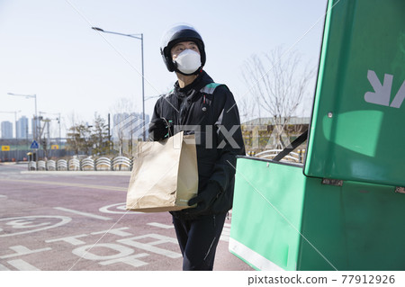 delivery male courier with mask on motorcycle, scooter delivering food, orders delivery male courier with mask on motorcycle, scooter delivering food, orders 77912926