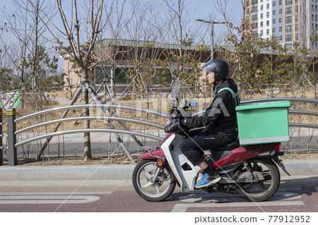 food delivery male courier riding motorcycle, scooter to deliver orders food delivery male courier riding motorcycle, scooter to deliver orders 77912952