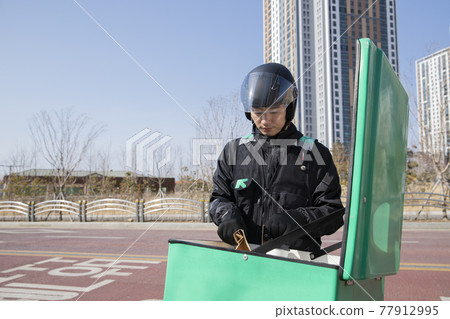 Asian delivery male courier on motorcycle, scooter delivering food, orders Asian delivery male courier on motorcycle, scooter delivering food, orders 77912995