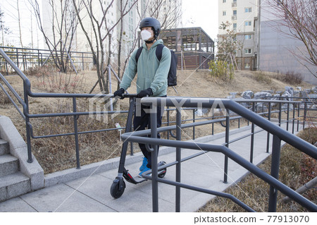 food delivery male courier with mask riding electric scooter to deliver orders food delivery male courier with mask riding electric scooter to deliver orders 77913070