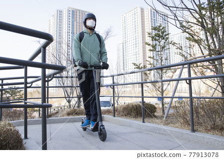 food delivery male courier with mask riding electric scooter to deliver orders food delivery male courier with mask riding electric scooter to deliver orders 77913078