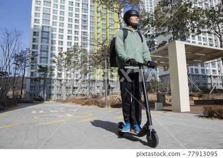 food delivery male courier riding electric scooter to deliver orders food delivery male courier riding electric scooter to deliver orders 77913095