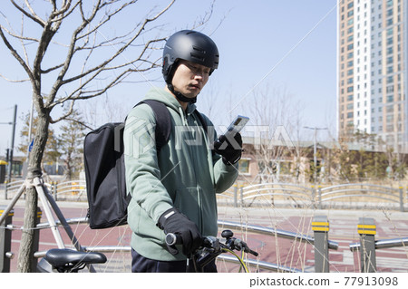 bike delivery service man checking order location with phone bike delivery service man checking order location with phone 77913098