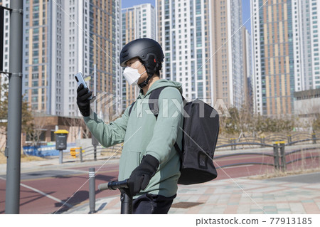 food delivery male courier riding electric scooter to deliver orders food delivery male courier riding electric scooter to deliver orders 77913185