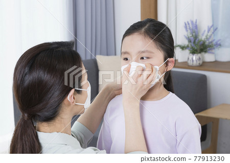 Asian mom helping daughter to wear mask, covid virus safety concept Asian mom helping daughter to wear mask, covid virus safety concept 77913230