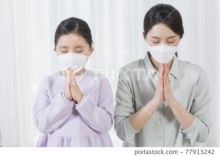 praying Asian mom and daughter wearing mask, covid virus safety concept 77913242