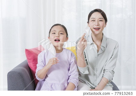 Asian mom and daughter removing masks and smiling Asian mom and daughter removing masks and smiling 77913263