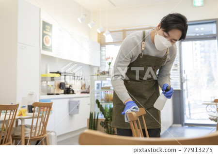 Asian man with mask sanitizing store during covid Asian man with mask sanitizing store during covid 77913275