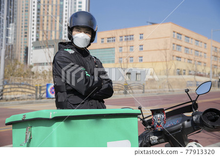 Asian food delivery male courier with mask beside motorcycle, scooter Asian food delivery male courier with mask beside motorcycle, scooter 77913320