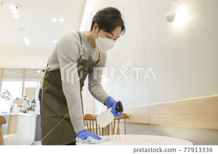Asian man with mask sanitizing store during covid 77913336