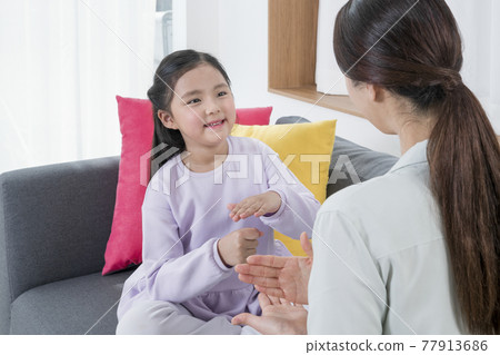 Asian mother and young daughter communicating in sign language 77913686