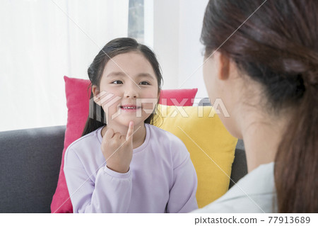 Asian mother and young daughter communicating in sign language 77913689