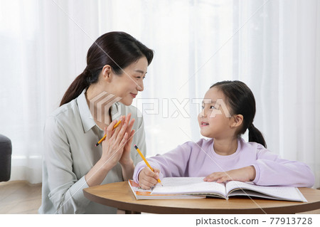 Asian mother helping young daughter study 77913728