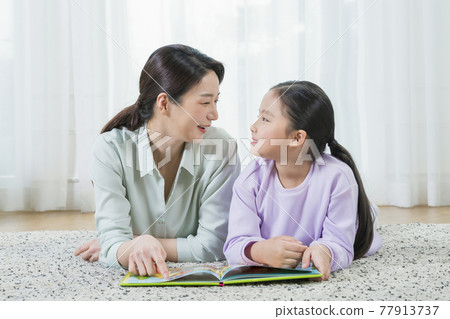 Asian mother and young daughter reading book Asian mother and young daughter reading book 77913737
