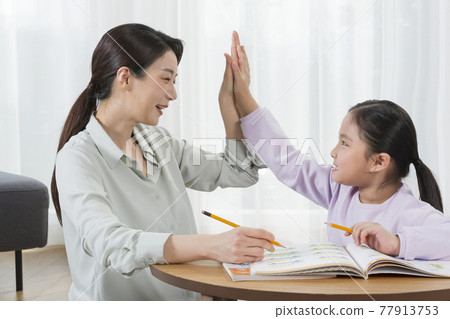 Asian mother helping young daughter study Asian mother helping young daughter study 77913753