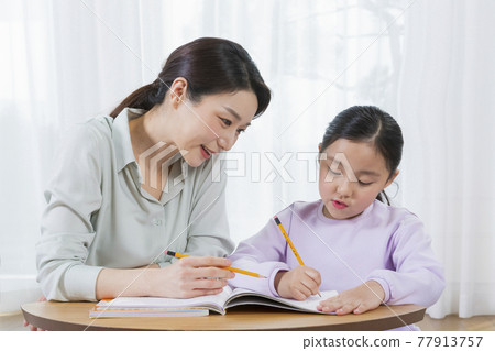 Asian mother helping young daughter study Asian mother helping young daughter study 77913757