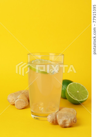 Glass of ginger beer and ingredients on yellow background Glass of ginger beer and ingredients on yellow background 77915395