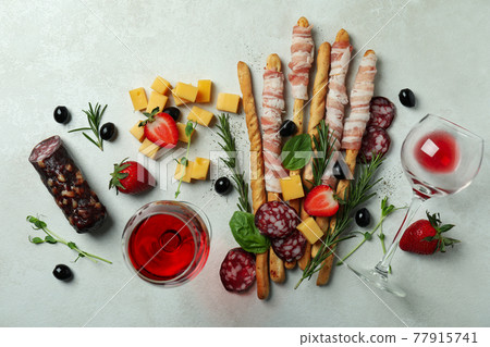 Grissini sticks with bacon, snacks and wine on white textured background Grissini sticks with bacon, snacks and wine on white textured background 77915741