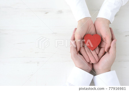 A heart-shaped object wrapped in the hands of men and women A heart-shaped object wrapped in the hands of men and women 77916981