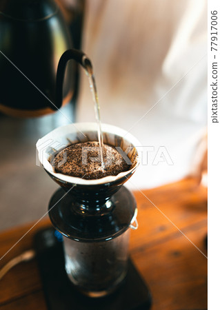 Drip coffee, barista pouring water on coffee ground with filter 77917006