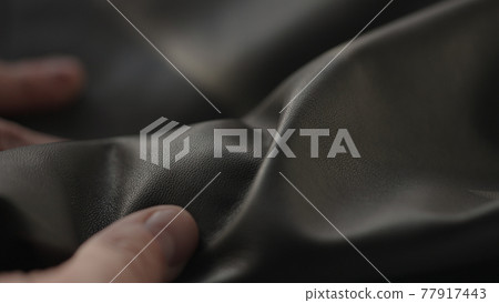 Man hand touching soft leather with sun shining from a window Man hand touching soft leather with sun shining from a window 77917443