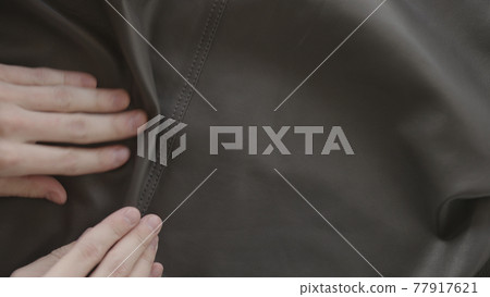 Top down shot of man hand inspecting soft gray leather Top down shot of man hand inspecting soft gray leather 77917621