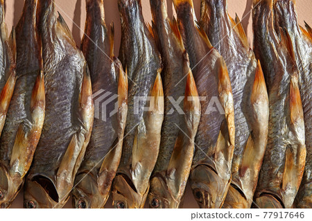 Some jerky or dried salty taranka, tasty clipfish on pink background. Popular beer snack. Traditional way of preserving fish. Close up 77917646