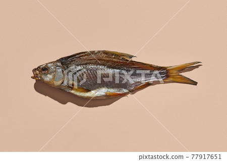 One jerky or dried salty roach, delicious clipfish on pink background. Famous beer appetizer. Traditional way of preserving fish. Close up 77917651