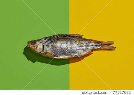 One jerky or dried salted roach, yummy clipfish on colorful background. Salty beer appetizer. Traditional way of preserving fish. Close up One jerky or dried salted roach, yummy clipfish on colorful background. Salty beer appetizer. Traditional way of preserving fish. Close up 77917653