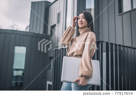 An asian young woman with a laptop An asian young woman with a laptop 77917654