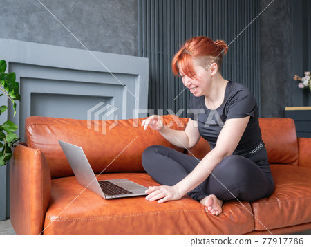 Red hair girl communicates online using a laptop Red hair girl communicates online using a laptop 77917786