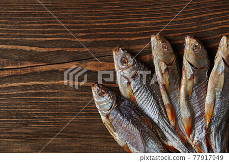 Dried or jerky salted roach, clipfish on wooden background. Salty beer appetizer. Traditional way of preserving fish. Close up 77917949