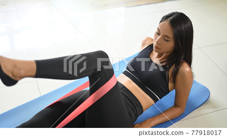 A beautiful woman is doing exercise in a comfortable living room. 77918017