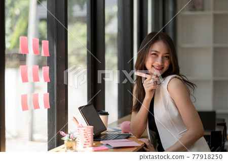 Portrait of attractive asian woman looking at camera smiling with confident working with smart tablet and positive lifestyle concept at cafe 77918250