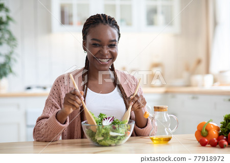 Happy Smiling African American Woman Preparing Fresh Vegetable Salad In Kitchen Happy Smiling African American Woman Preparing Fresh Vegetable Salad In Kitchen 77918972