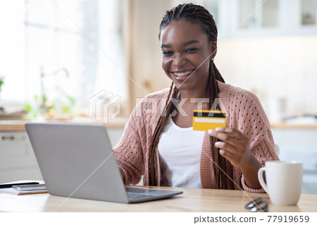 Online Payments. Black Female Holding Credit Card And Using Laptop In Kitchen Online Payments. Black Female Holding Credit Card And Using Laptop In Kitchen 77919659