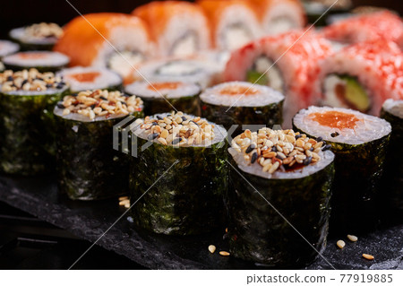 Close up of sliced sushi roll sprinkled with sesame seeds on top. Close up of sliced sushi roll sprinkled with sesame seeds on top. 77919885