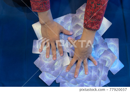Close-up hands of fortune teller who shuffle Tarot cards for predict the fate and future next step, Divine magic and occultism concept, dark side concept, Top-view 77920037